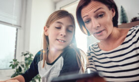 Parent showing teen son how to set up iPhone Screen Time parental controls